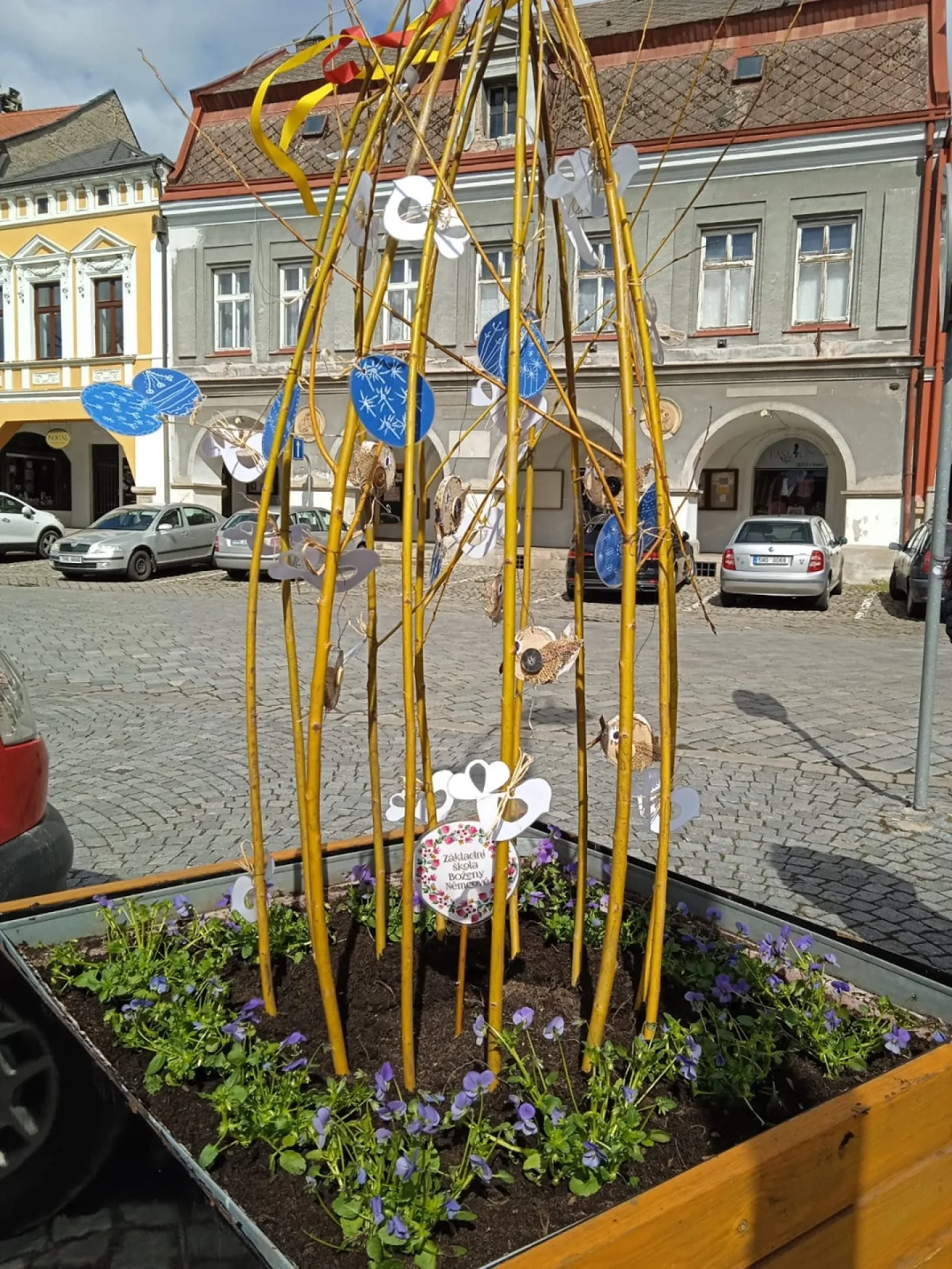 Květináč s maceškami, vrbovými proutky a výzdobou z keramických výrobků a dalšími jarními dekoracemi